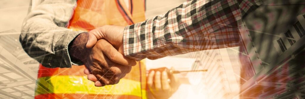 Two professionals shaking hands on a construction site, symbolising partnership and successful project collaboration in the building industry.